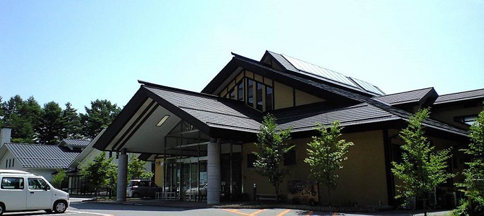 大きな三角屋根の建物で、入口がガラス張りのながたの湯の外観写真