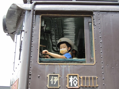 電気機関車ED19-1の運転席に座り駅員の帽子を被った子供が、ポーズをとっている様子を外から撮影した写真
