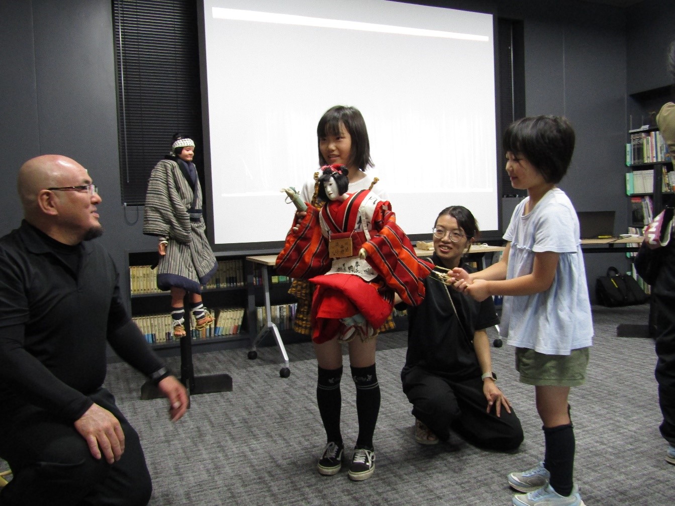女の子二人と保存会の方1人でお鶴を操っている。子供たちは嬉しそうに笑っている