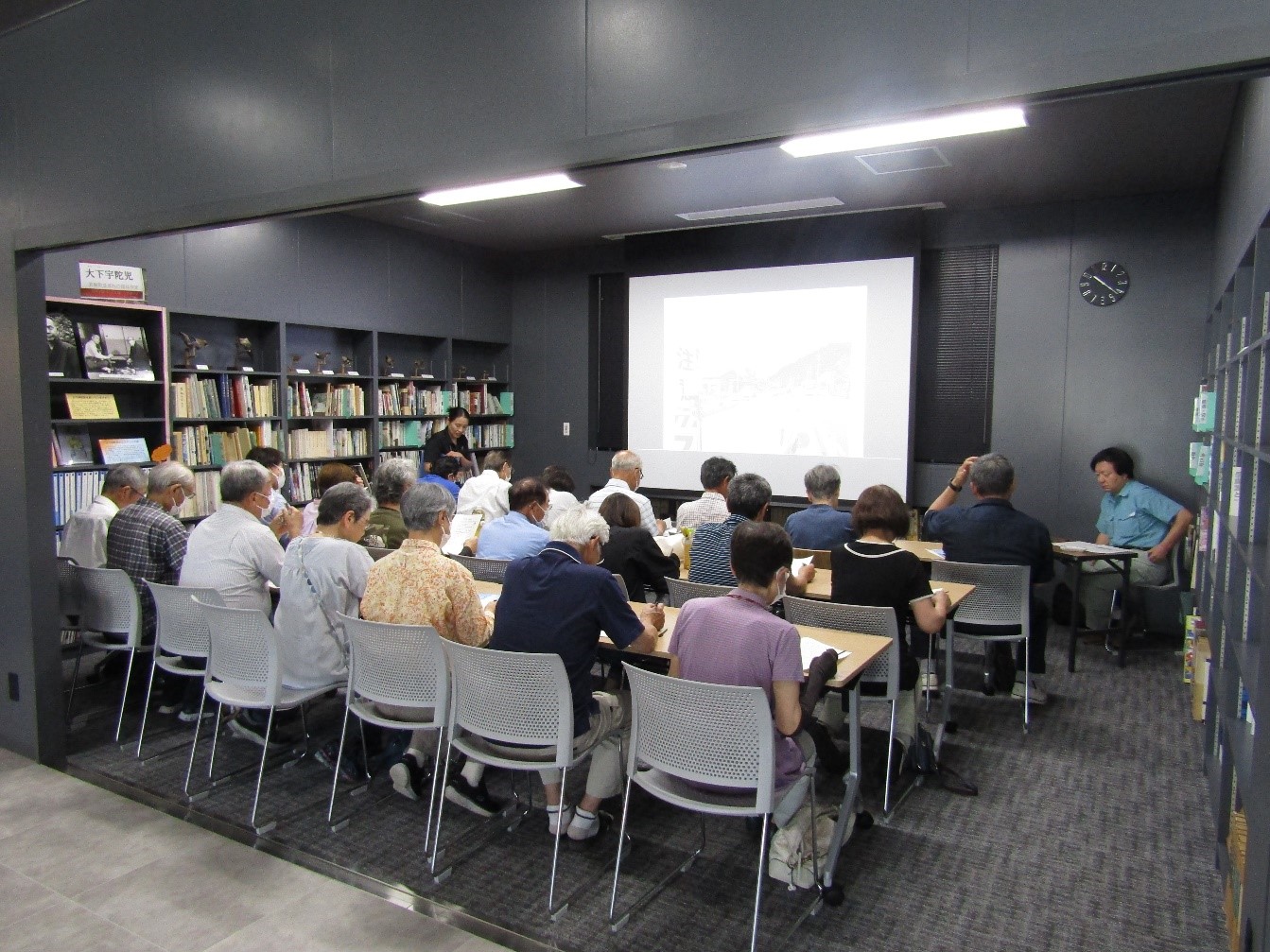博物館内の図書講座室で、講師の白沢さんが20名の参加者の前で話をしている