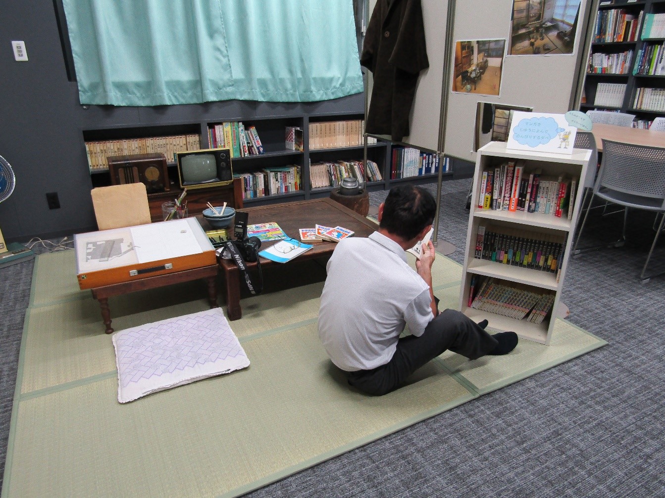 再現されたコーナーでマンガを読む男性