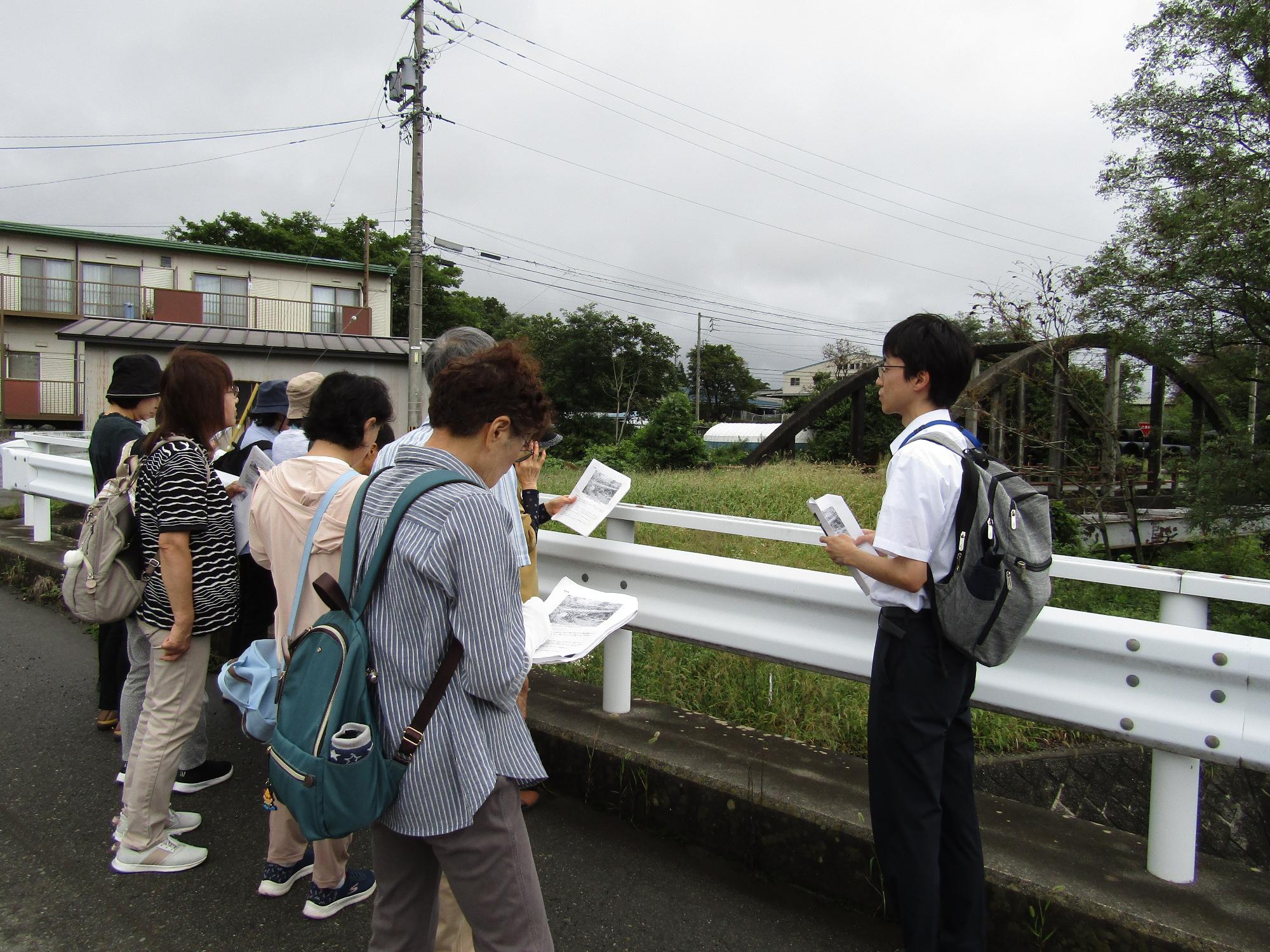 富島橋を見ながら、博物館職員の説明を聞く参加者