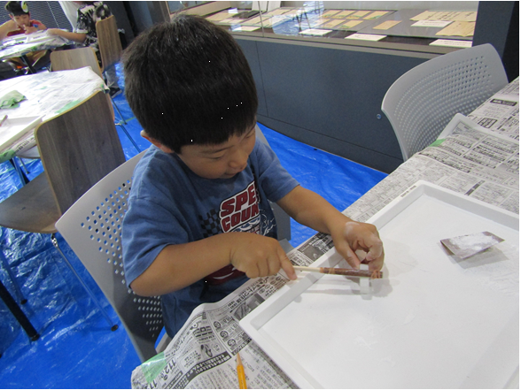 紙やすりでまが玉を作る男の子