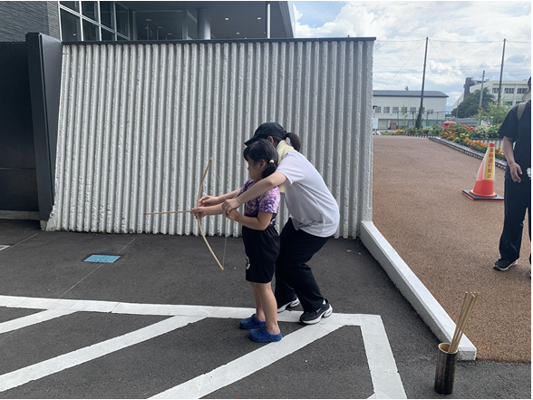 弓矢を職員と体験する女の子