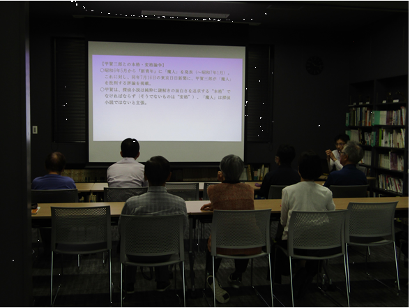 図書講座室で椅子に座りスクリーンを見ながら、話を聞く参加者の皆さん