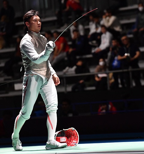 白色のユニフォームを着用した西藤選手が、観客の前でマスクを外し右手に持った剣を前に出している様子の写真