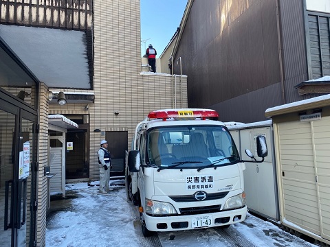 正面に「災害派遣」と書かれたトラックが医療施設の建物前に停車し、作業員の方が給水作業を行っている様子の写真