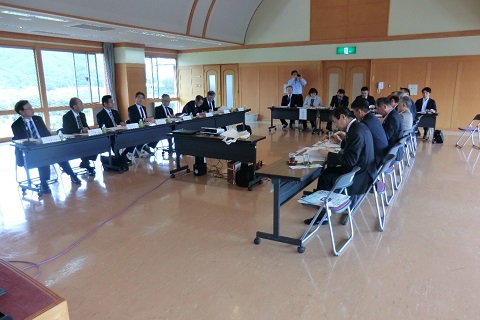 コの字に設置された長机の席に議員の方々や関係者が座り机の上に置かれた資料を見ている、視察研修の様子の写真