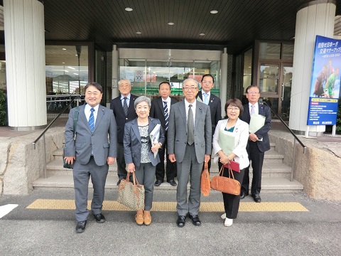 左右に円柱型の柱が立つ建物の前で、前列に4名後列に4名の議員の方々が横2列に並んでいる写真