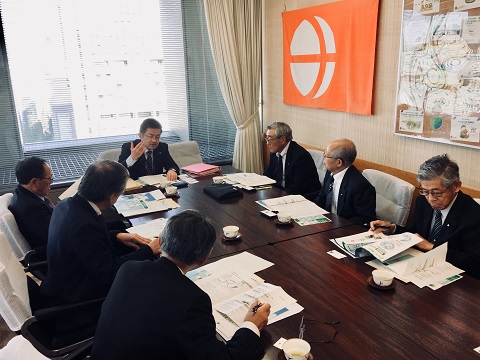 大きな長机を囲み上座に座った吉沢所長が参加者に説明をしている様子の写真