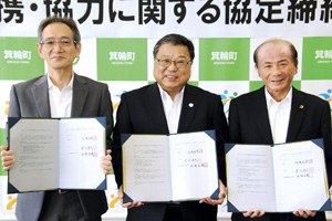 箕輪町のバックパネルの前で、町長を中央に2名の関係者と協定書を開いて持ち横一列に並んでいる写真