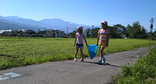 のどかな畑の中の農道をあるいている二人の娘さんの写真