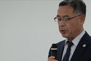 マイクを持ち話をしている男性をアップで写した写真