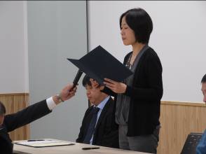 マイクを差し出された女性が起立し、宣言書を手に持ち宣言書を読み上げている様子の写真