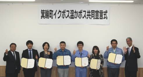 8名の方が横一列に並び、そのうちの6名の方が宣言書を手に持ち記念撮影をしている写真