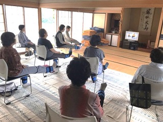 椅子に腰かけて右足を伸ばして体操をしている参加者の写真