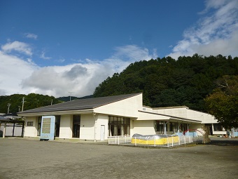広い園庭の奥に白い外壁をした園舎がある三日町保育園の外観写真