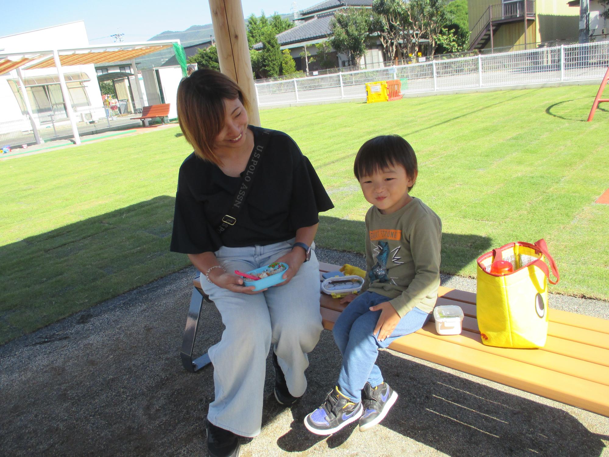 芝生庭のベンチでお弁当を食べる親子