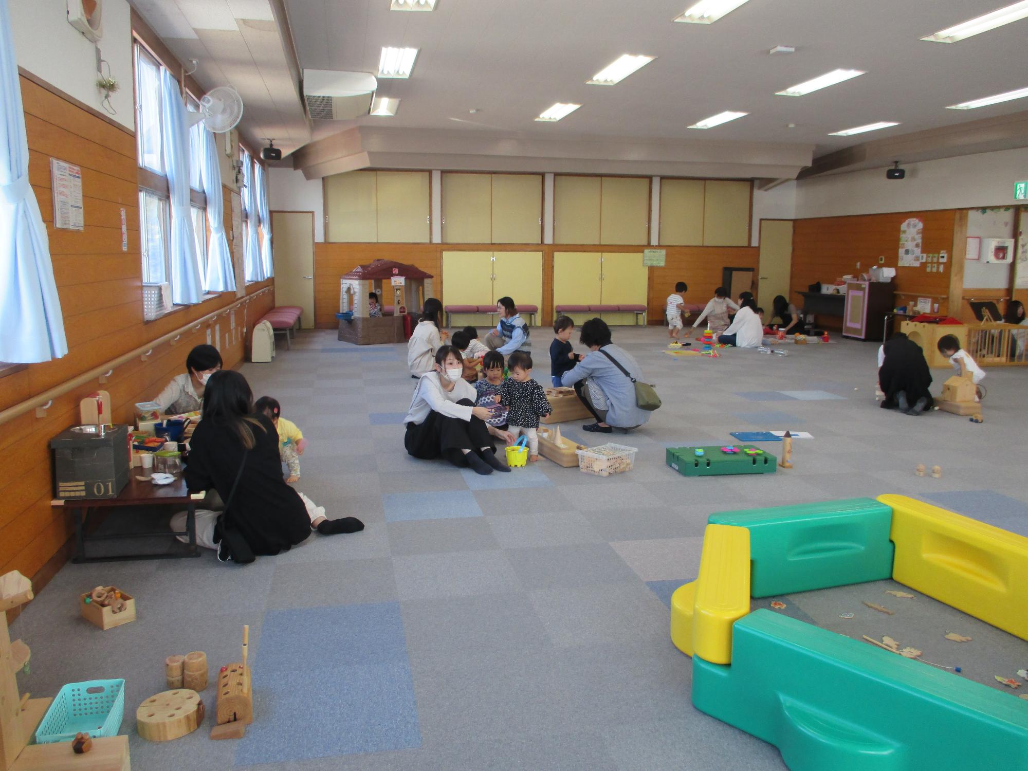 広い会場に大勢の親子が床に座りそれぞれのおもちゃであそんでいる。