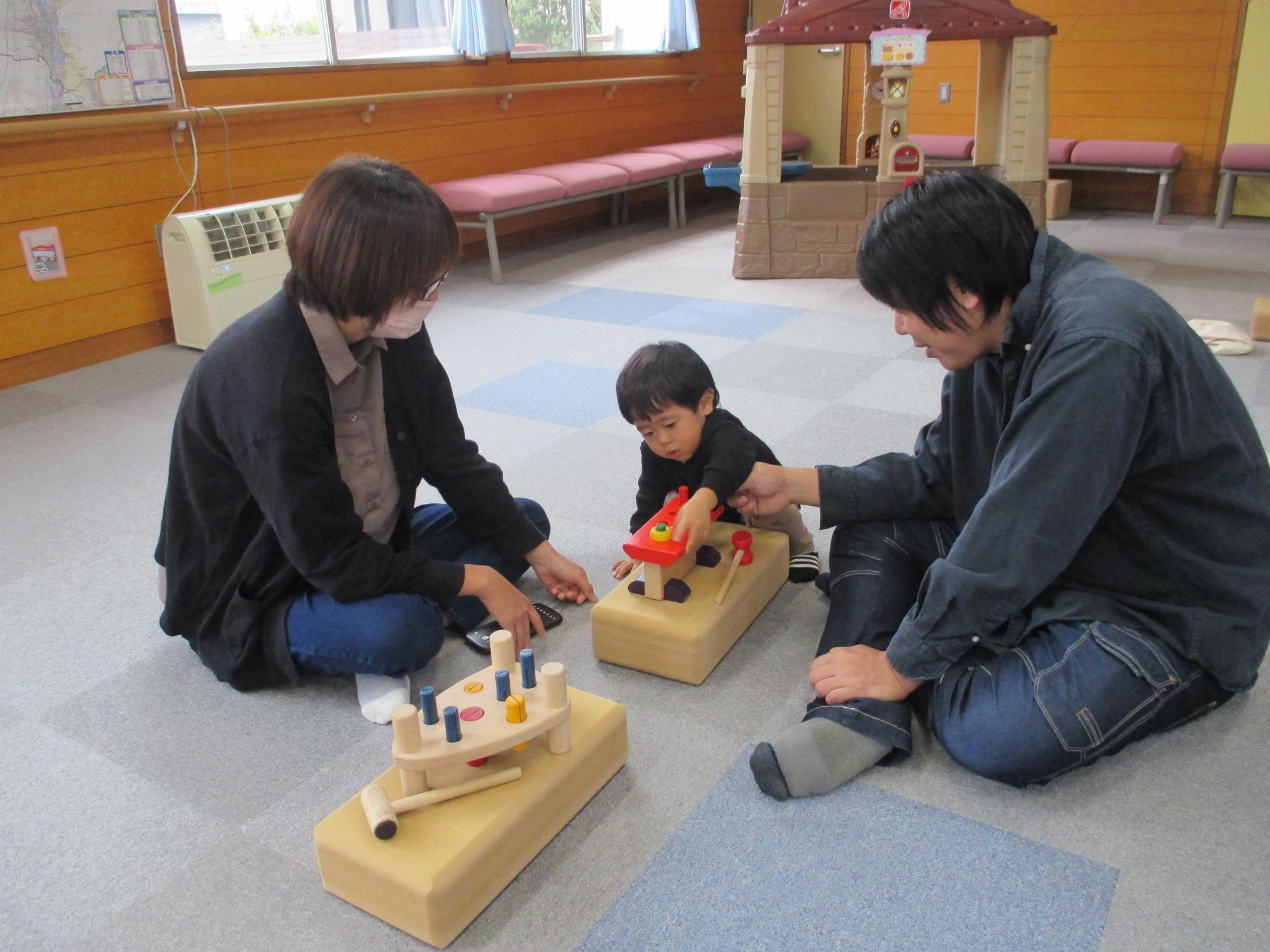 木製おもちゃであそぶ両親と子