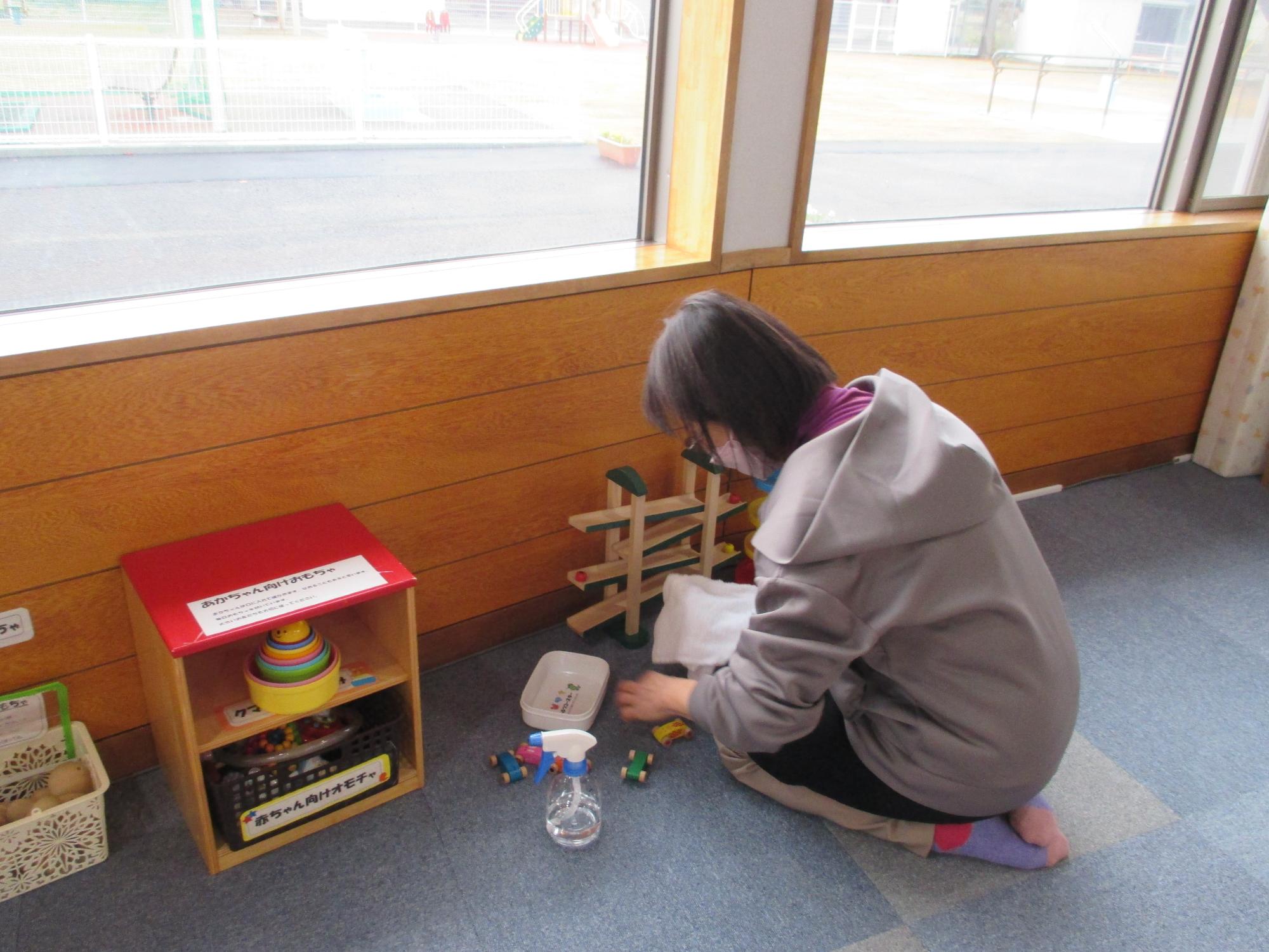 部屋の壁に向かって座り車のおもちゃを拭いている