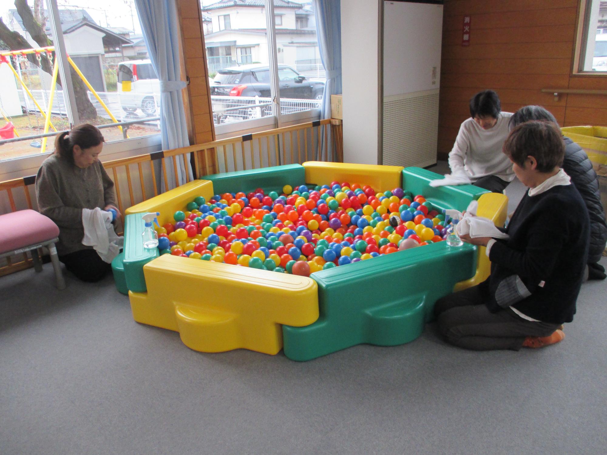 ボールプールの周りに女性4人が座りボールを拭いている