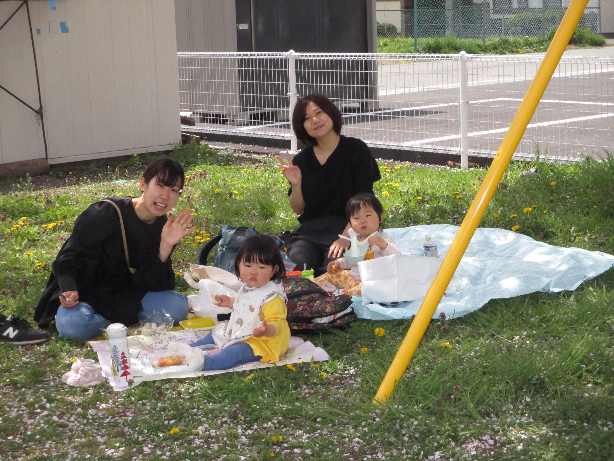 戸外で母子2組がシートを敷いてランチ