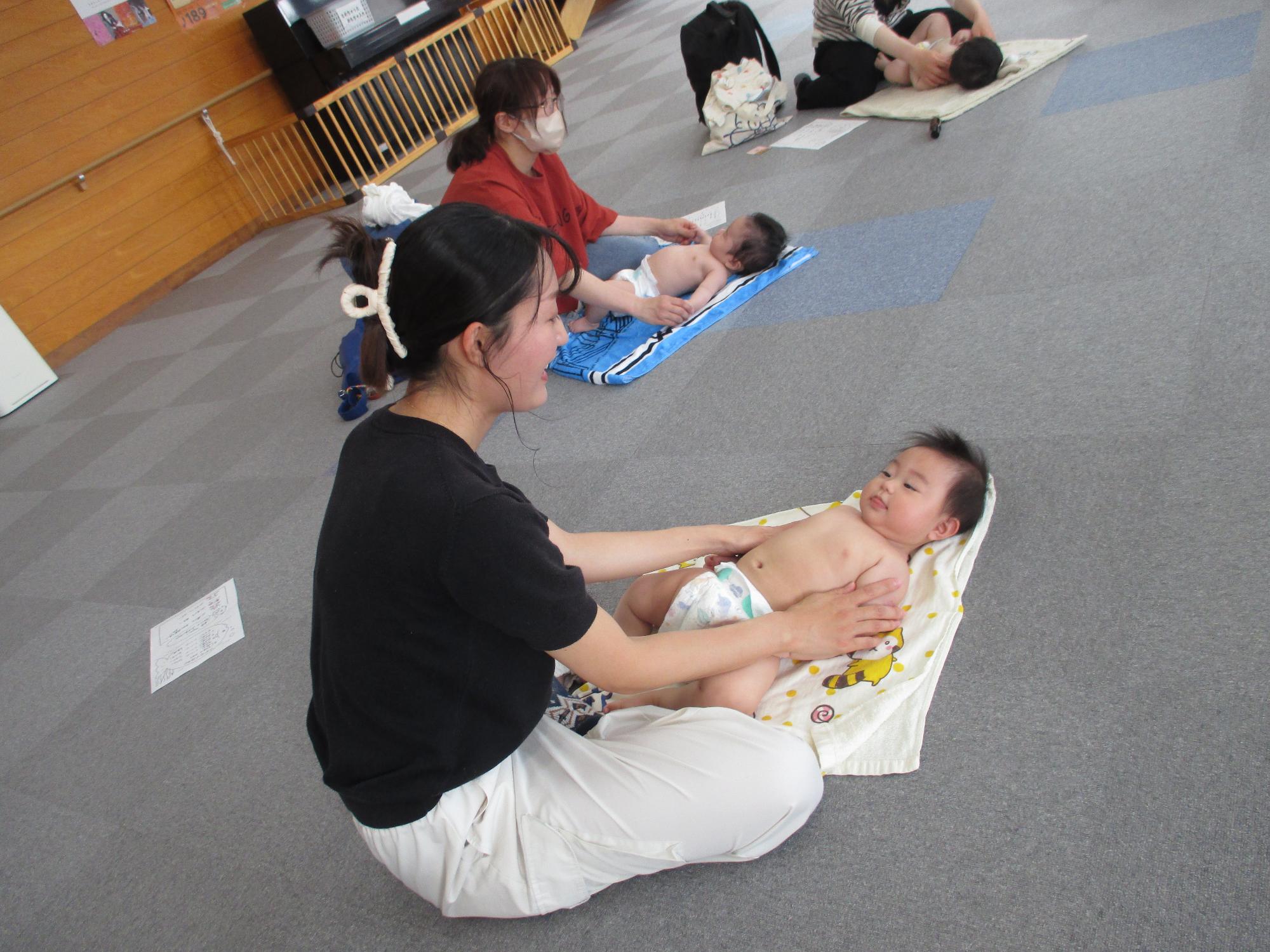 裸で寝かせた赤ちゃんと目を合わせている母