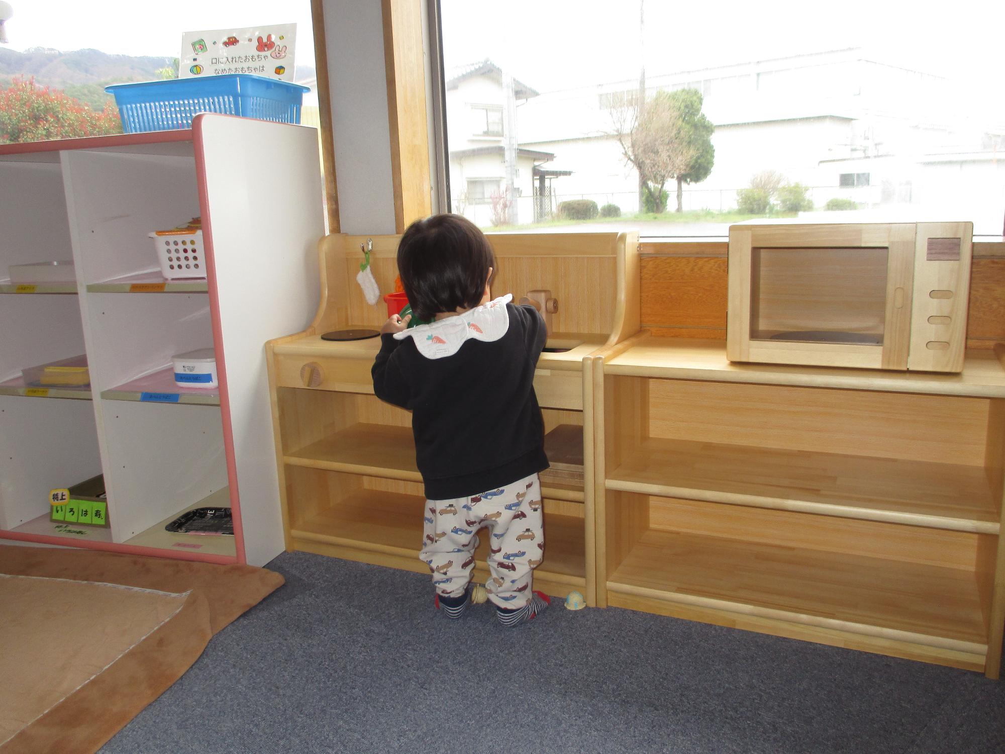 木製流し台付きレンジで遊ぶ1歳児の後ろ姿