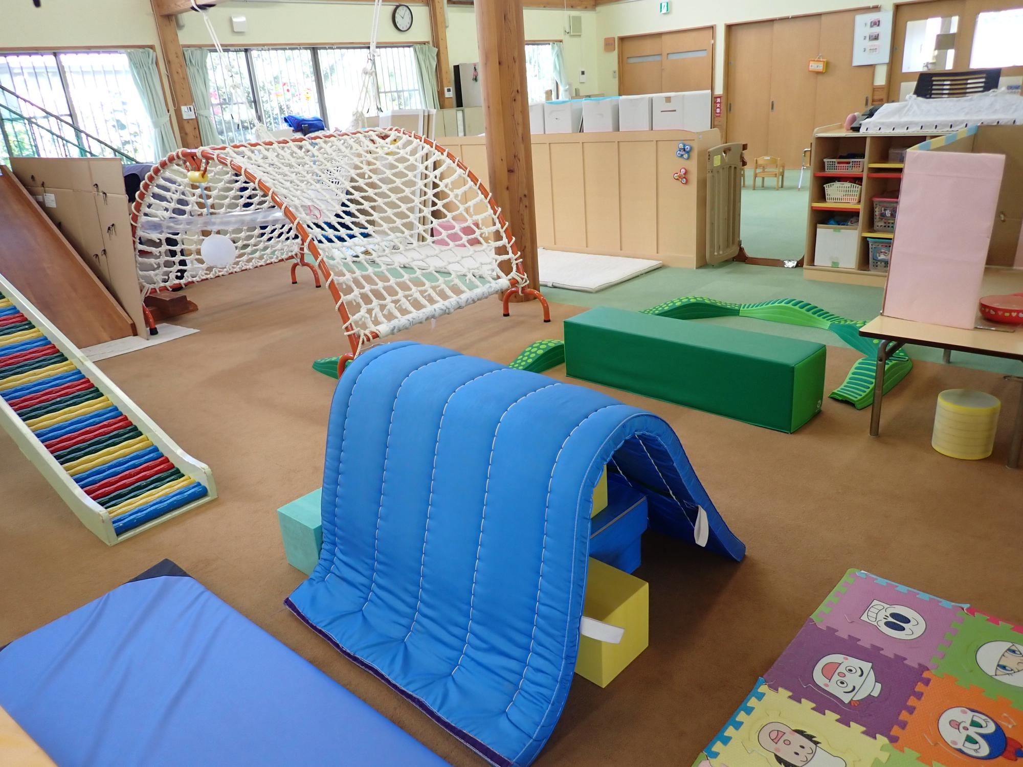 若草園のプレイルームの様子 カラフルな滑り台やネットのたいこ橋などの遊具があります