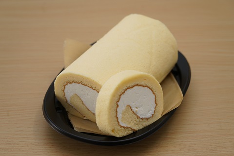 真ん中にクリームが巻かれたロールケーキがお皿にのせられ1切れのロールケーキが横に添えられた写真