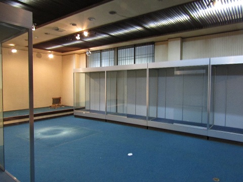 引っ越しが始まった博物館内の展示物が移動され、壁側に設置されたガラスの引き戸のショーケースだけが残っている部屋の写真