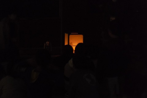 電気が消された室内で、照明が灯された行燈の明かりを近くで覗いている児童たちの写真