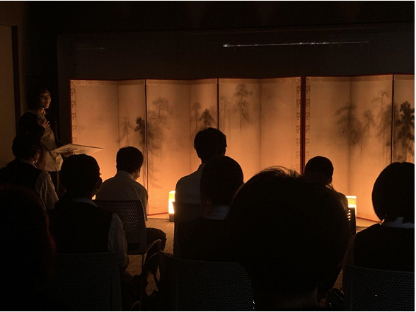 ろうそくの光をイメージした、オレンジ色の行燈の光に照らされた屏風を見る中学生