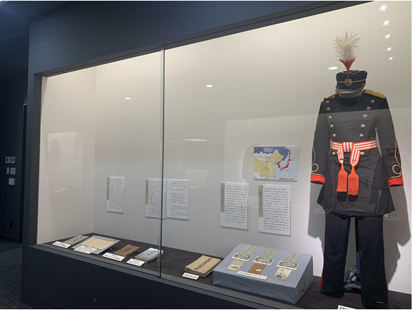 展示ケース内には、本、ポストカード、軍服、制帽が展示されている