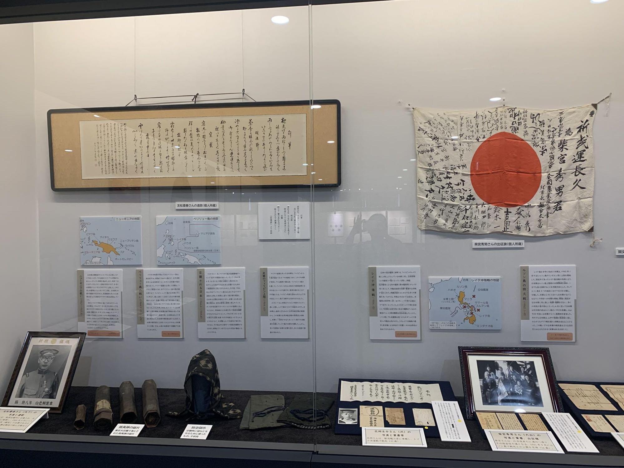 展示ケースには、戦争で亡くなった方の遺影や手紙、防空頭巾、日章旗が展示してある