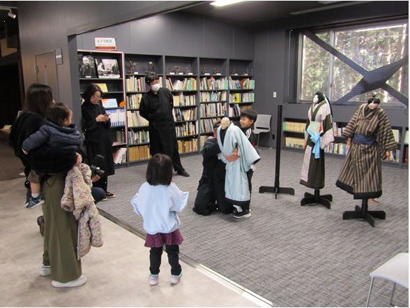 男児が人形操りを体験している。その様子を家族が見守っている