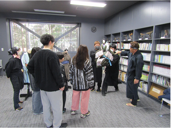 3人の保存会員が人形操りを披露し、家族がその様子をみている