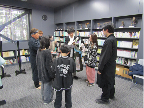 男性と女性が人形操り体験をし、保存会員さんが教えている