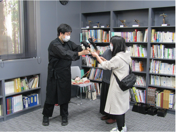 人形の頭だけを持ち、保存会の方が参加者に説明し、触ってもらっている