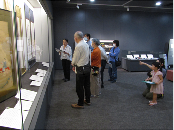 美術展示室で学芸員の話を聞きながら絵を鑑賞する参加者の皆さん