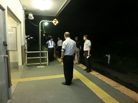 駅のホームで、制服姿の警察官の話を左腕に腕章をつけた3名の男性が聞いている夜間巡視活動の様子の写真