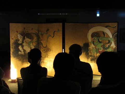 照明を落とした室内で、白色の光を照らし浮き上がった「風神雷神図屏風・夏秋草図屏風」の写真