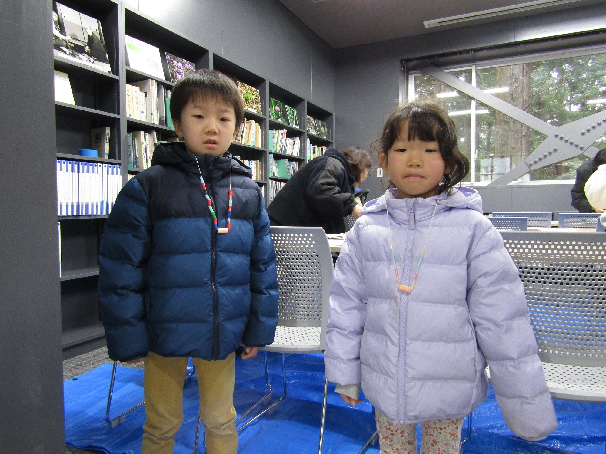 完成したペンダントを首から下げて並ぶ男の子と女の子