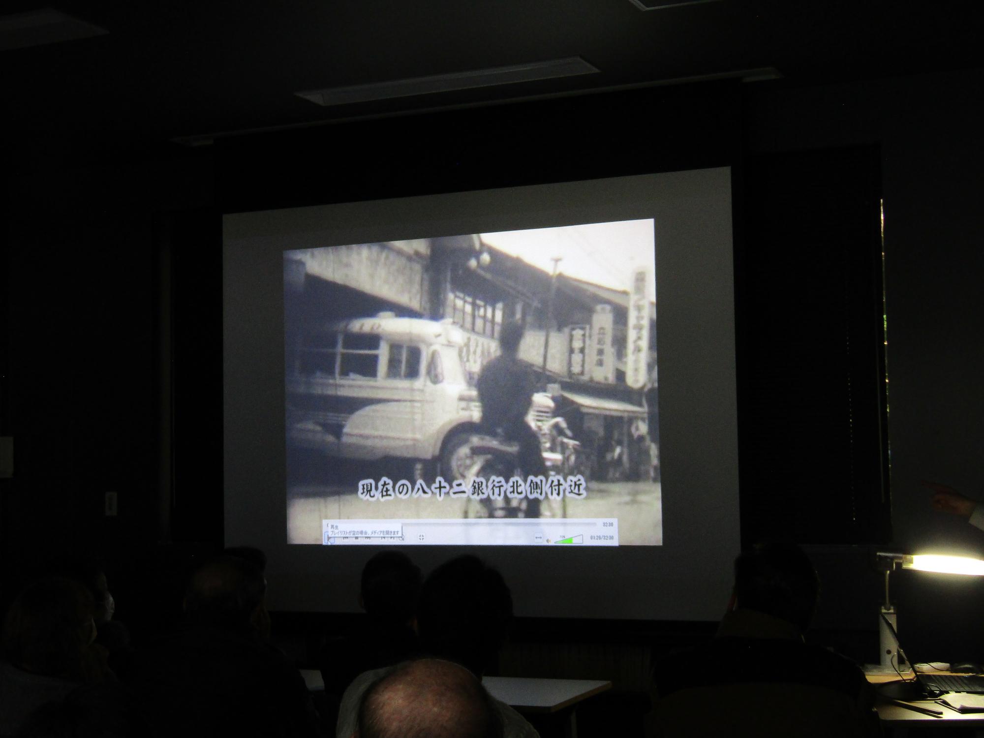 昭和30年代の役場付近の映像。当時の役場は現在の八十二銀行箕輪支店付近にあった。バスが車庫に入ろうとしている。