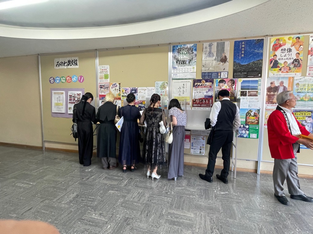 投票記載台で6人の男女が記載している所を後ろから写した写真