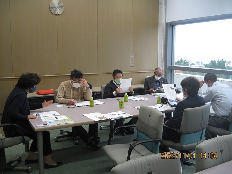 大きな窓ガラスが設置された室内で、左端に座っている男性の話を6名の議員の方々が聞いている視察の様子の写真