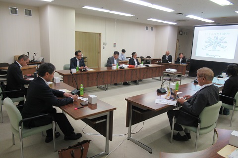 前方に資料が映し出されたスクリーンが設置され、コの字に設置された長机に議員の方々が座っている視察の様子の写真