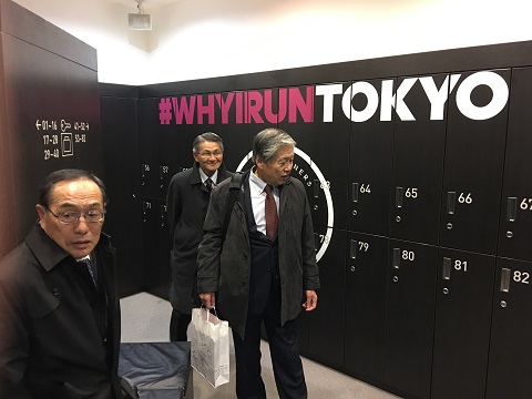 真っ黒なロッカーにピンクと白で「#WHYIRUNTOKYO」と書かれたロッカールームを視察する関係者の写真
