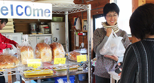 店頭に並んでいる焼きたてのパンと接客をしている奥様の写真